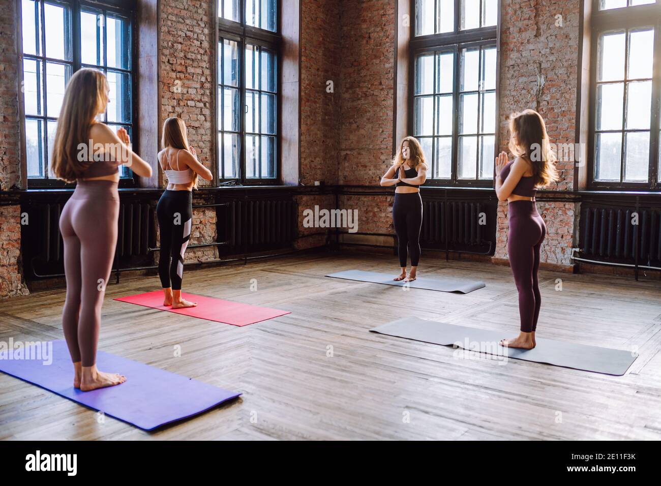 Quatre Jeunes Femmes Font Complexe Dasanas De Yoga étirant Dans La Classe De Style Loft Les 